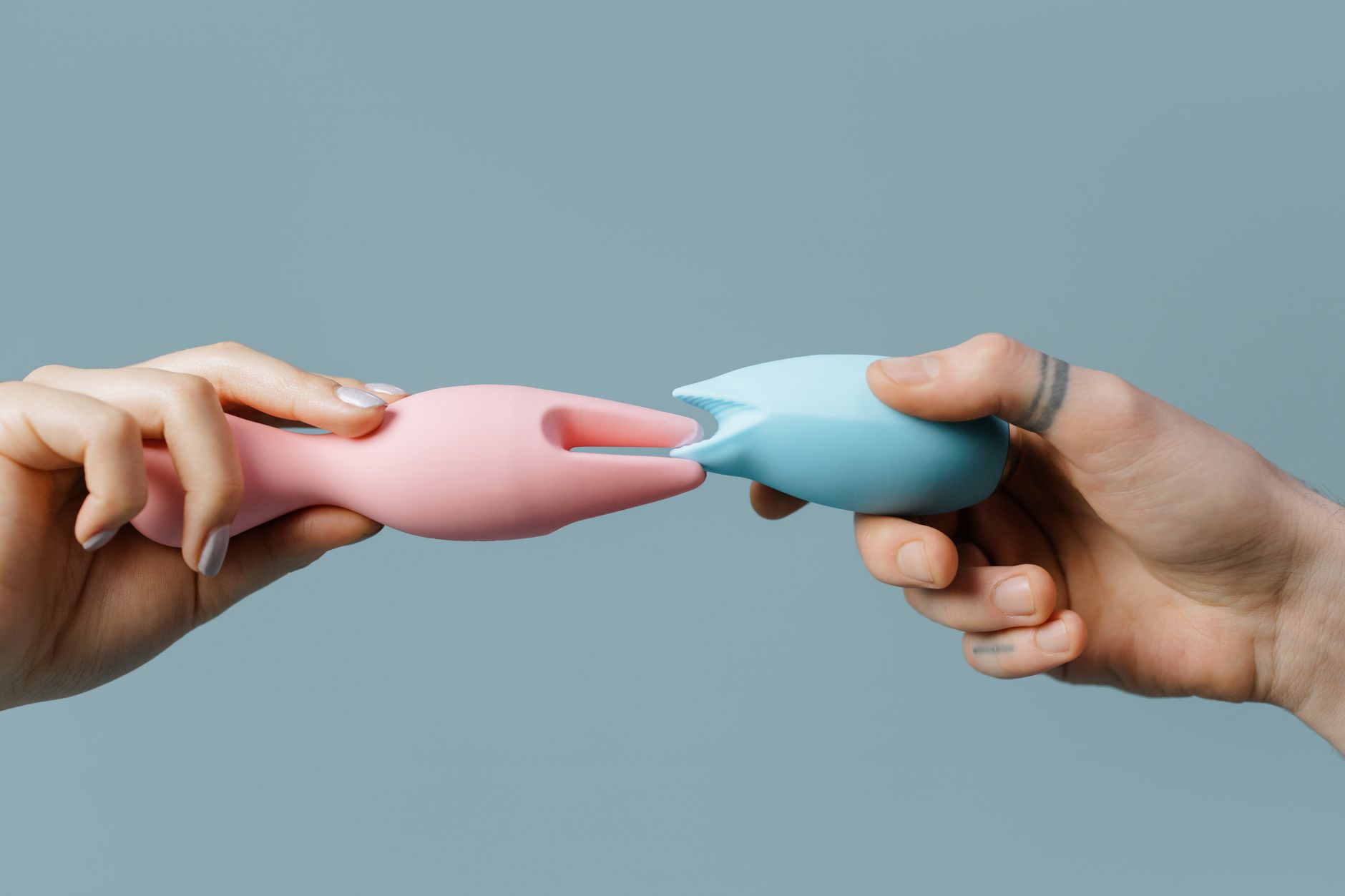 Hands holding pastel-colored silicone toys, representing intimacy and reconnection