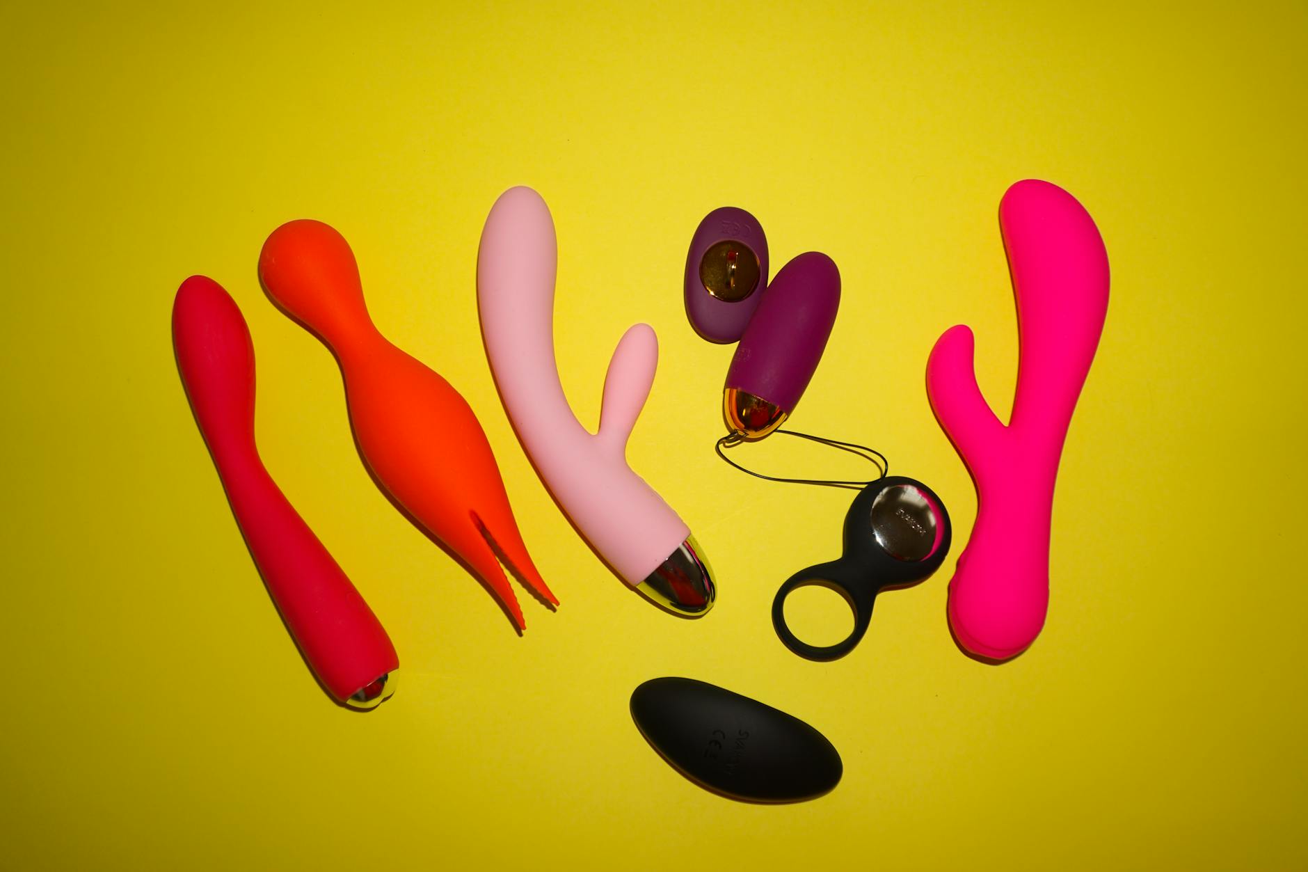 Colorful silicone vibrators and intimate toys arranged on a bright background