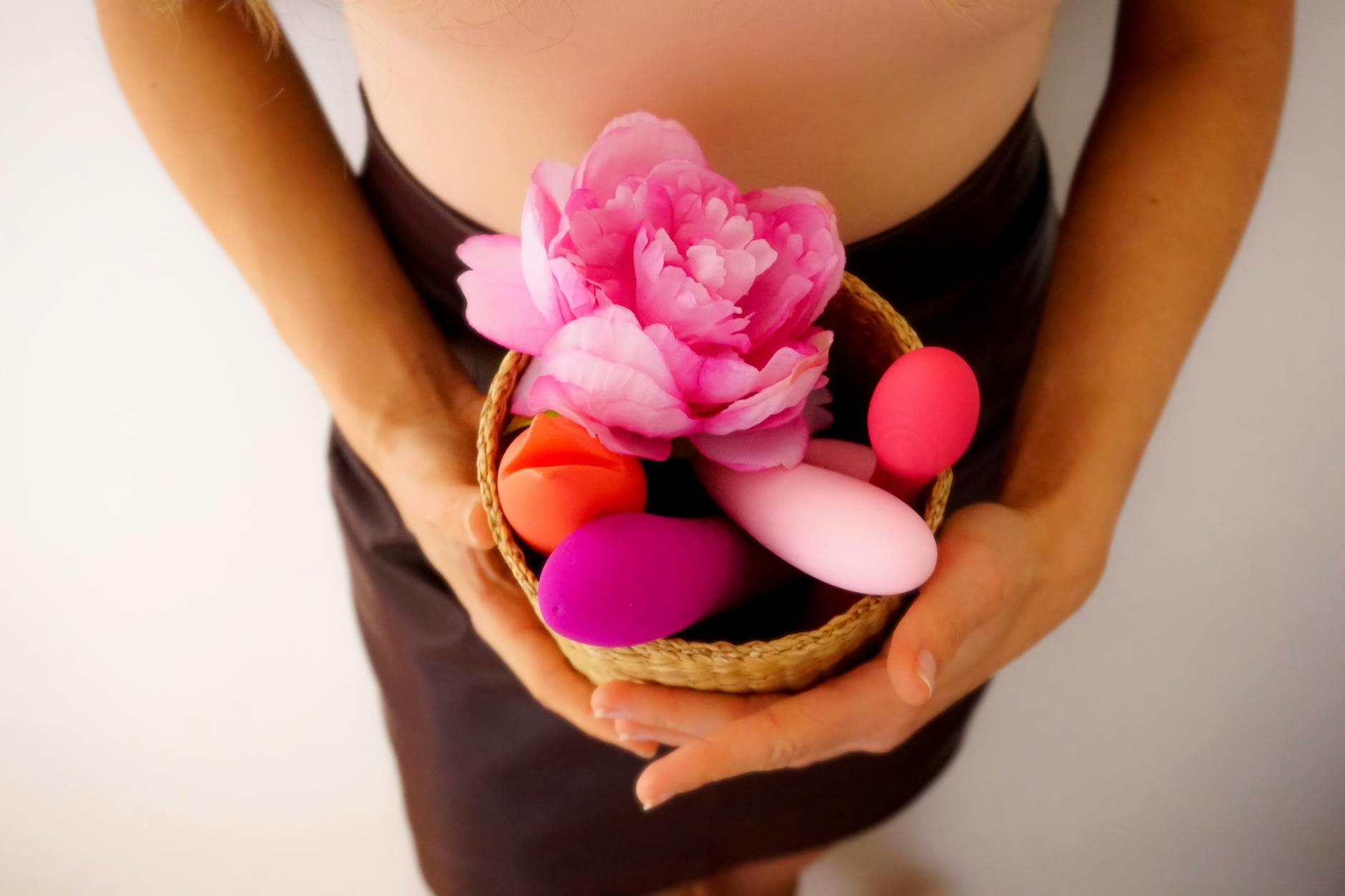 A collection of colorful vibrators and intimate wellness toys arranged in a woven basket
